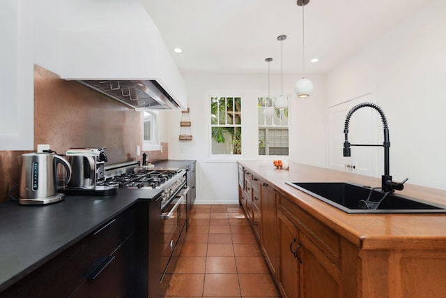 kitchen featuring high end range, a sink, pendant lighting, tile patterned floors, and exhaust hood