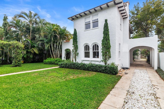 mediterranean / spanish home with a front lawn and stucco siding