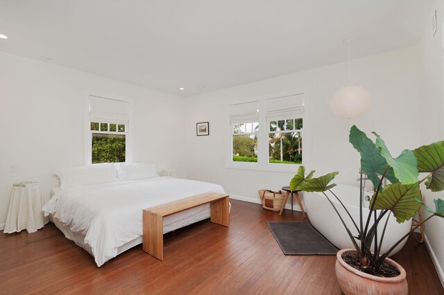 bedroom featuring recessed lighting, multiple windows, baseboards, and wood-type flooring