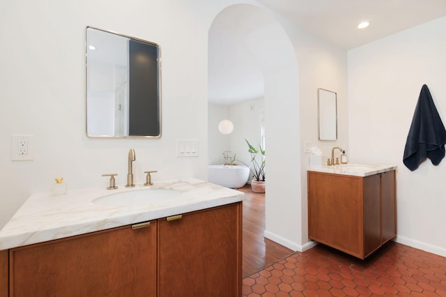 full bathroom featuring two vanities, recessed lighting, baseboards, and a sink