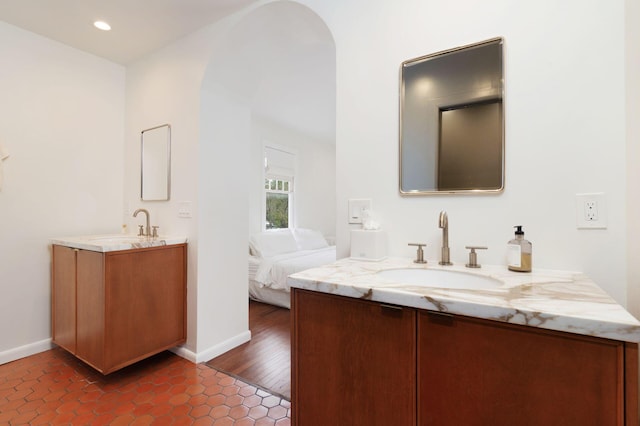 full bathroom with two vanities, recessed lighting, baseboards, and a sink