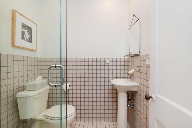 bathroom featuring tile walls, toilet, and a wainscoted wall