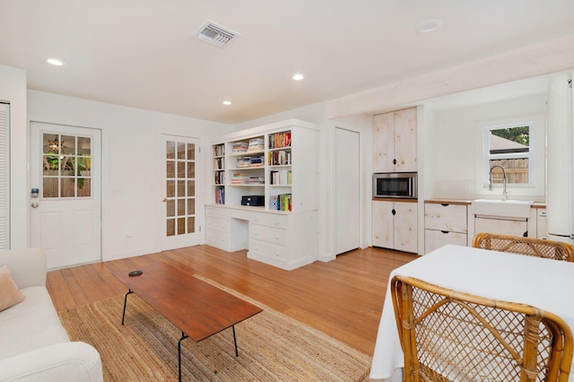 living area featuring built in desk, recessed lighting, light wood-style floors, and visible vents