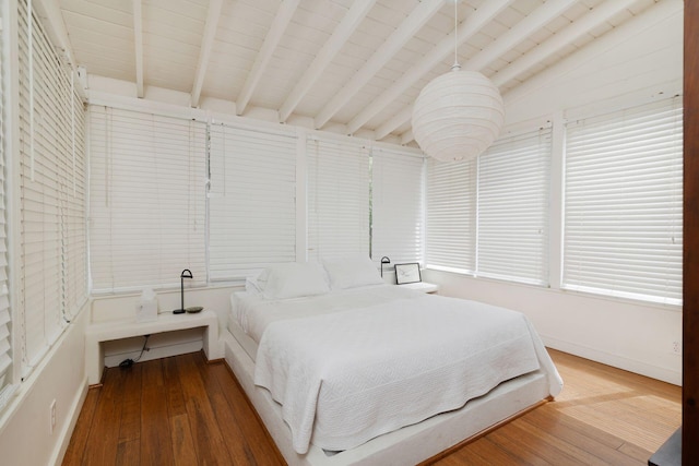 bedroom featuring wood finished floors and vaulted ceiling with beams