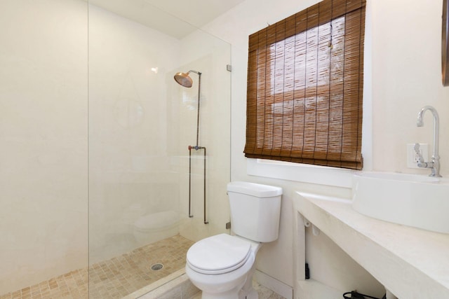 bathroom with walk in shower, toilet, baseboards, and a sink