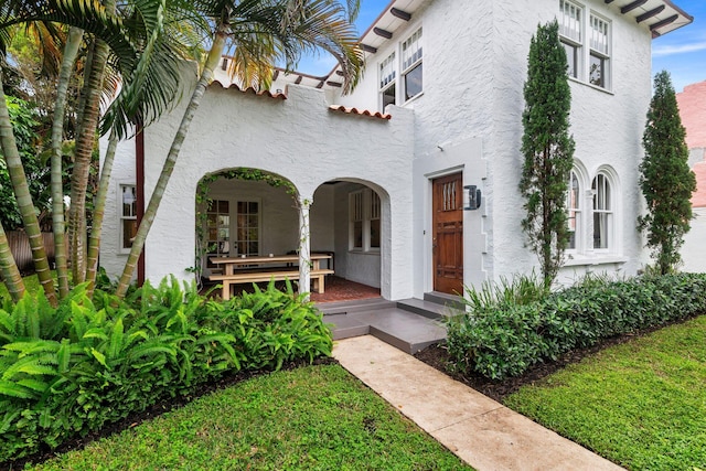 mediterranean / spanish house featuring a porch, stucco siding, and a tiled roof