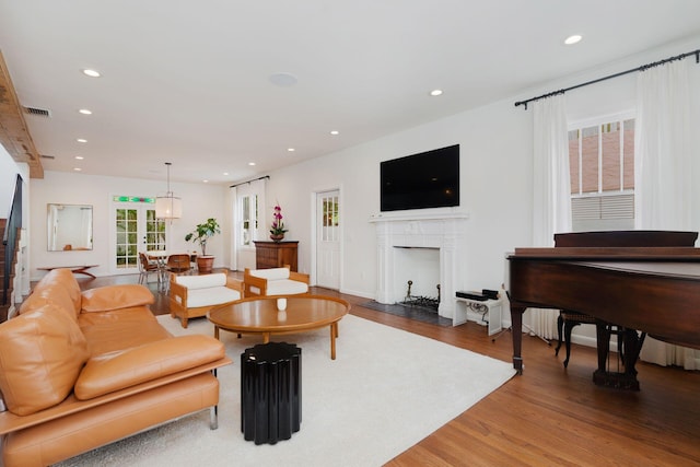 living room with recessed lighting, wood finished floors, visible vents, and a fireplace with flush hearth