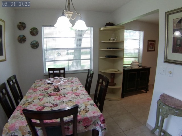 dining space with light tile patterned flooring, plenty of natural light, and a chandelier