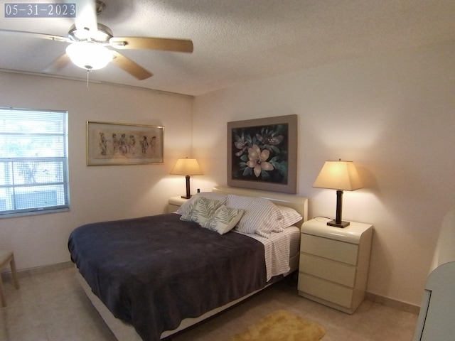 bedroom with light tile patterned floors, a textured ceiling, baseboards, and ceiling fan