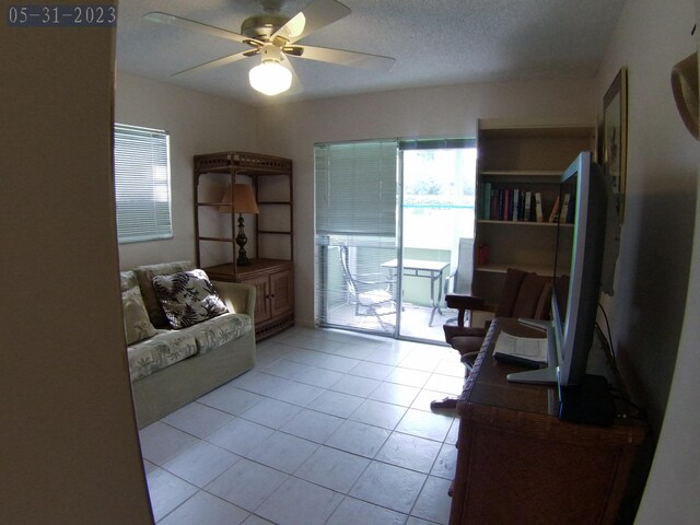 living area with light tile patterned flooring, a textured ceiling, and a ceiling fan