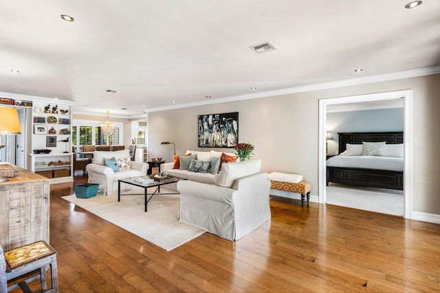 living area with baseboards, visible vents, wood-type flooring, crown molding, and a notable chandelier