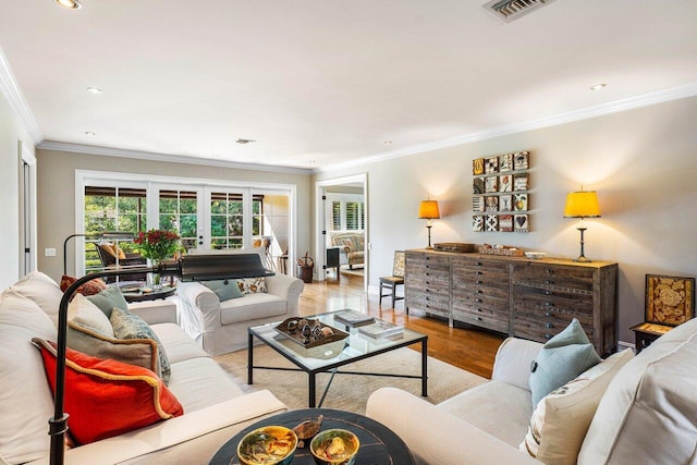 living area with recessed lighting, wood finished floors, visible vents, and ornamental molding