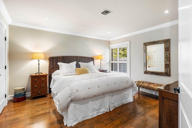 bedroom with visible vents, baseboards, hardwood / wood-style floors, and ornamental molding