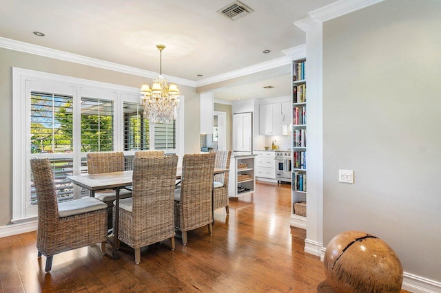 dining room with an inviting chandelier, visible vents, wood-type flooring, and ornamental molding