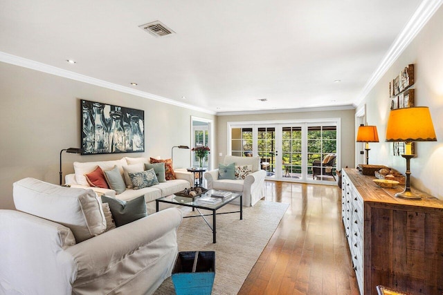 living area featuring visible vents, light wood-type flooring, and ornamental molding