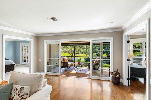 doorway to outside with visible vents, hardwood / wood-style floors, and ornamental molding