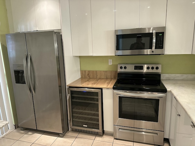 kitchen with beverage cooler, white cabinets, stainless steel appliances, and light countertops