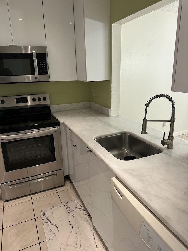 kitchen featuring light stone countertops, a sink, appliances with stainless steel finishes, modern cabinets, and marble finish floor