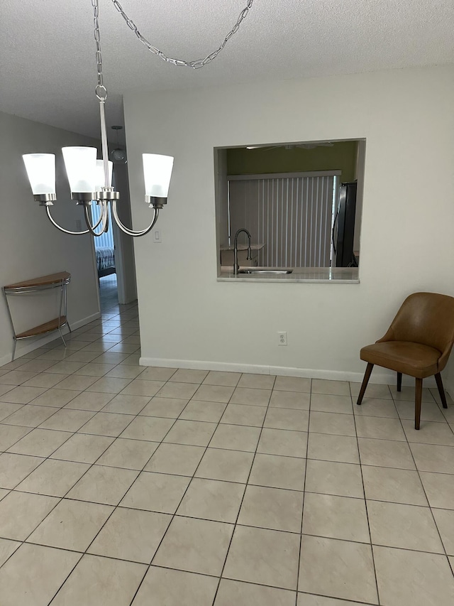 dining area with light tile patterned floors, a textured ceiling, and baseboards