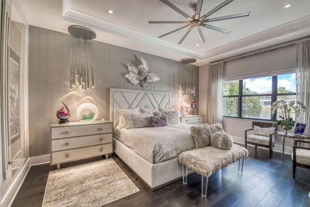 bedroom with a tray ceiling, dark wood-style flooring, and ornamental molding