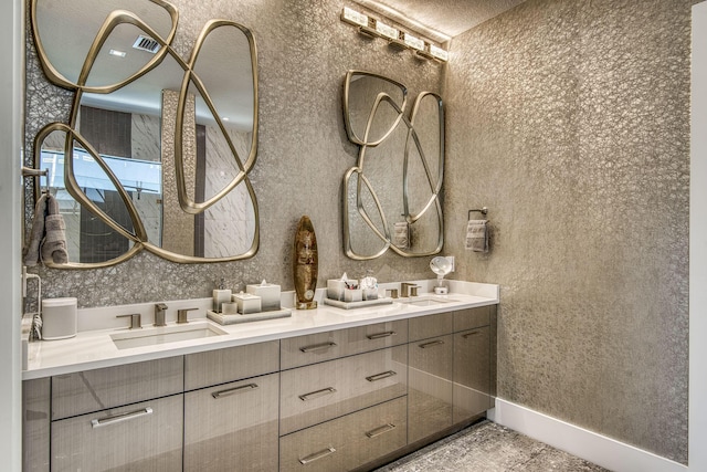 bathroom featuring a sink, baseboards, and double vanity