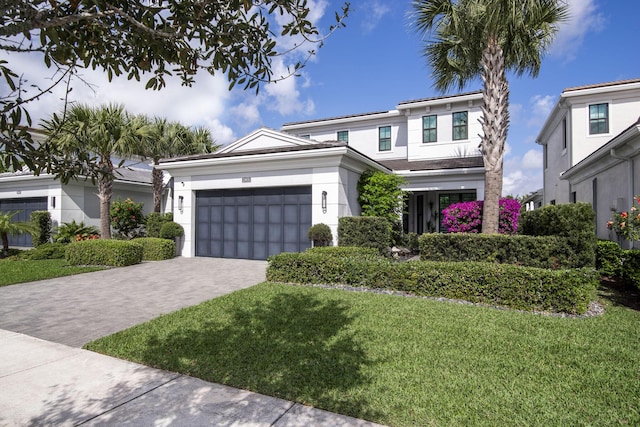 view of front of property with a front lawn, decorative driveway, a garage, and stucco siding