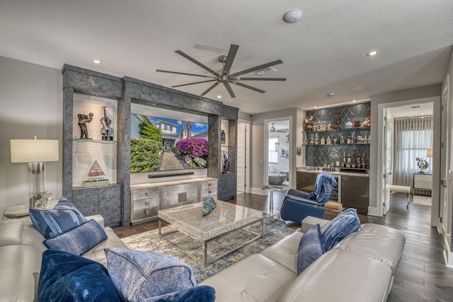 living area with a bar, recessed lighting, wood finished floors, and a textured ceiling