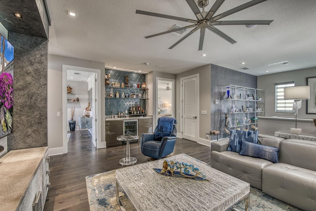 living area with wine cooler, dark wood finished floors, a dry bar, and a textured ceiling