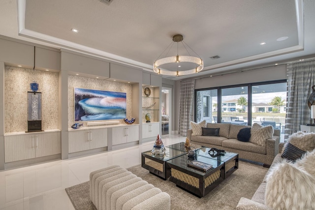 living room featuring a raised ceiling, visible vents, and wainscoting