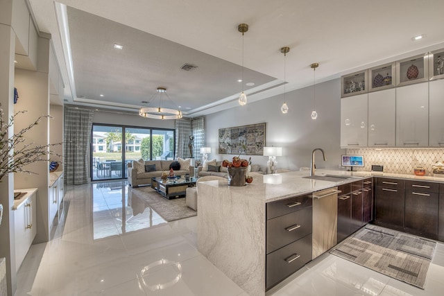 kitchen featuring a sink, a tray ceiling, stainless steel dishwasher, and dark brown cabinetry