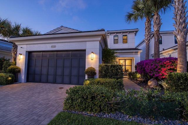 view of front of house with stucco siding, decorative driveway, and an attached garage