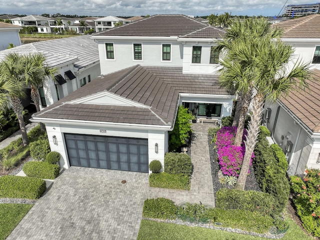 view of front of home with a residential view, a tiled roof, stucco siding, decorative driveway, and an attached garage