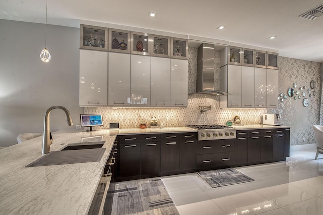 kitchen featuring visible vents, a sink, stainless steel gas stovetop, wall chimney exhaust hood, and modern cabinets