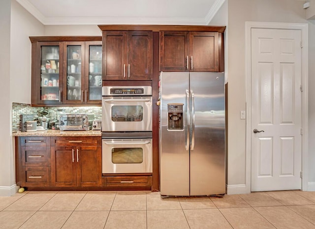 kitchen featuring crown molding, light tile patterned flooring, glass insert cabinets, and appliances with stainless steel finishes