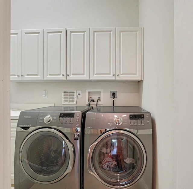 laundry area featuring cabinet space, visible vents, and washing machine and clothes dryer