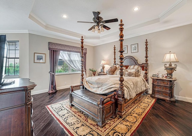 bedroom featuring a tray ceiling, wood-type flooring, baseboards, and crown molding