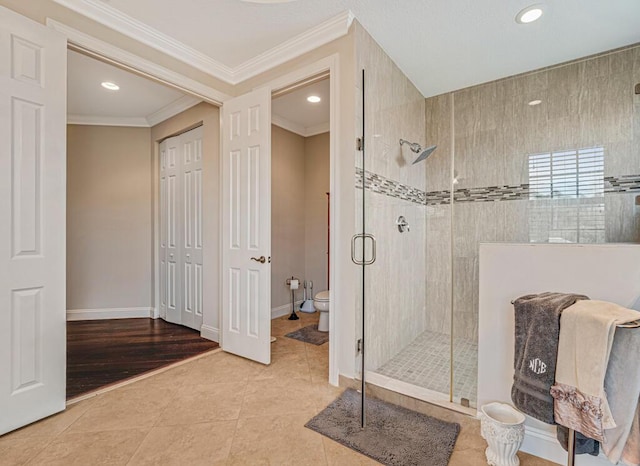 full bathroom featuring tile patterned floors, toilet, a shower stall, crown molding, and baseboards