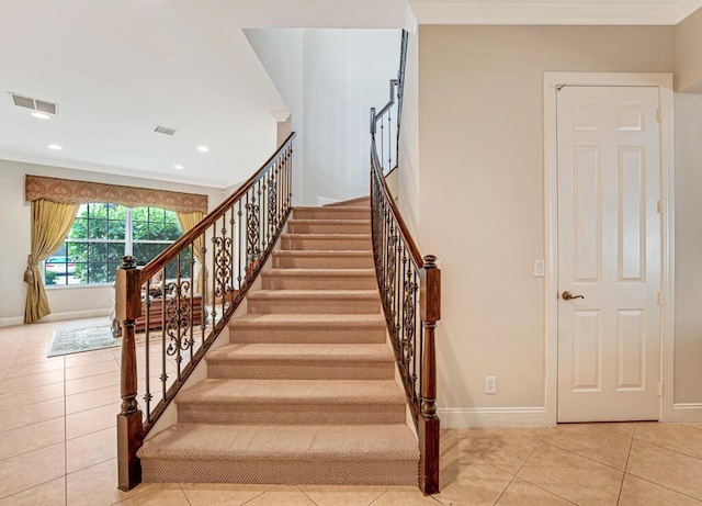 staircase with tile patterned floors, crown molding, visible vents, and baseboards