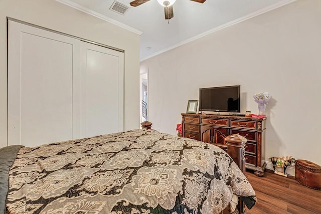 bedroom featuring wood finished floors, visible vents, ceiling fan, a closet, and crown molding