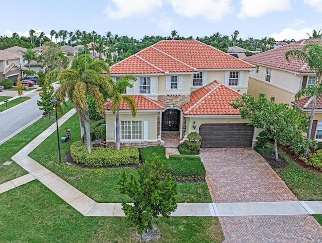 mediterranean / spanish house with stone siding, stucco siding, a tiled roof, and decorative driveway