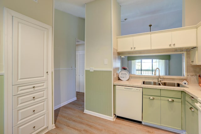 kitchen featuring light wood-style flooring, white dishwasher, a sink, wainscoting, and green cabinets