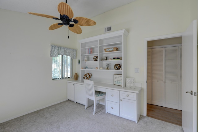 office with light carpet, visible vents, a ceiling fan, and built in desk