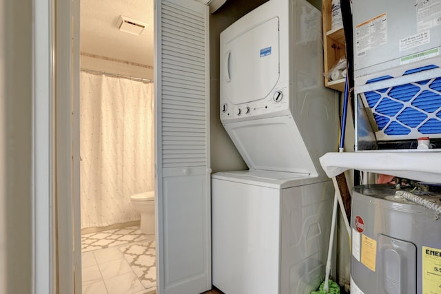 laundry area featuring water heater, laundry area, and stacked washer and clothes dryer