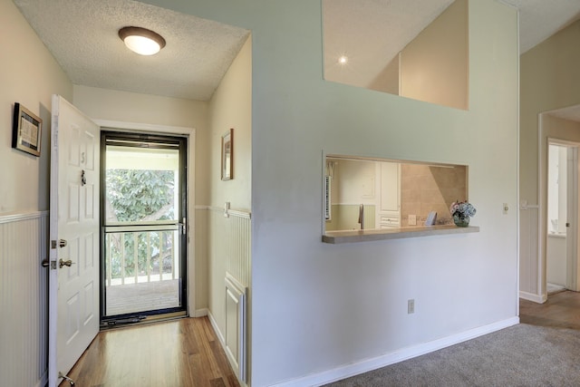 foyer with a textured ceiling, baseboards, and wood finished floors