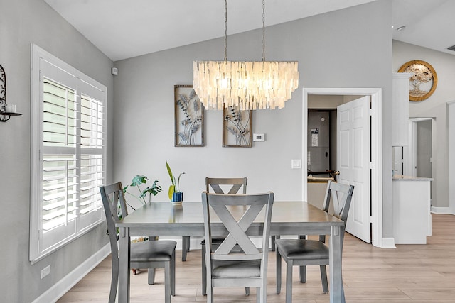 dining room with baseboards, light wood finished floors, a chandelier, and vaulted ceiling