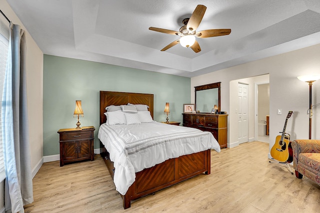 bedroom with baseboards, a raised ceiling, ceiling fan, and light wood finished floors