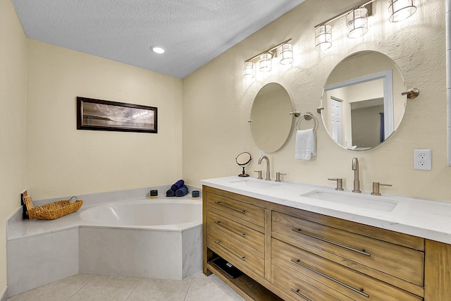 bathroom featuring a textured ceiling, tile patterned floors, a garden tub, and a sink