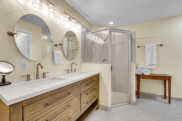 bathroom with a stall shower, a textured ceiling, and a sink