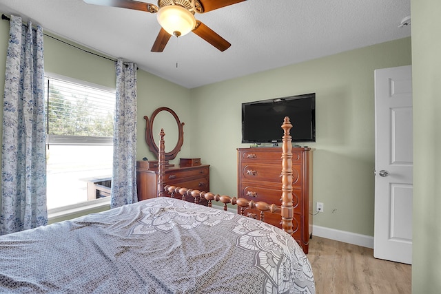 bedroom with a textured ceiling, a ceiling fan, baseboards, and wood finished floors