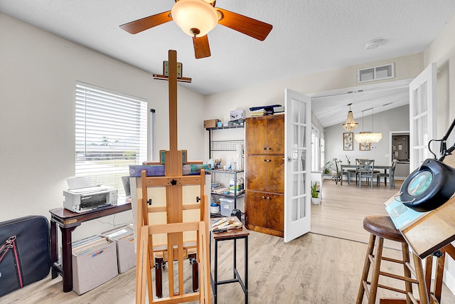 office featuring visible vents, ceiling fan with notable chandelier, a textured ceiling, wood finished floors, and vaulted ceiling